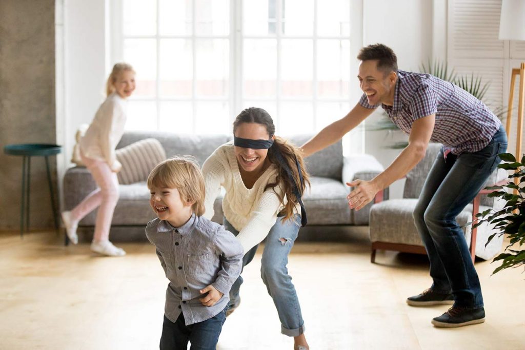 Happy family in the living room playing the blindfold game