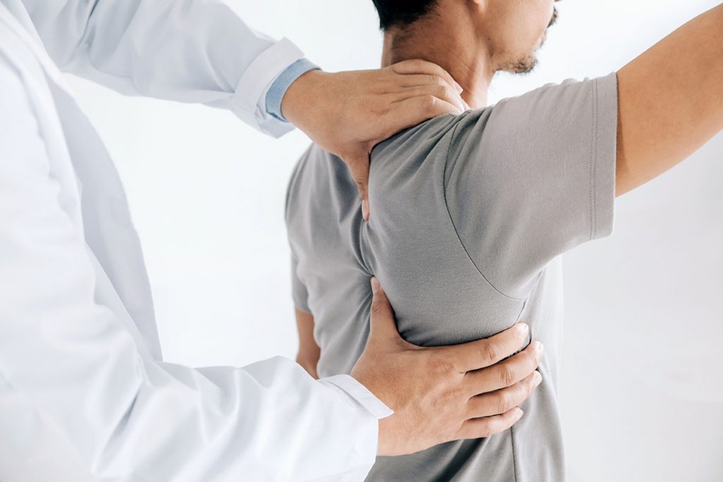 chiropractor pressing a man's shoulders to analyze the pain